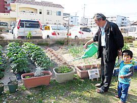 ご近所のお子さんと一緒に、畑の野菜に水やり中