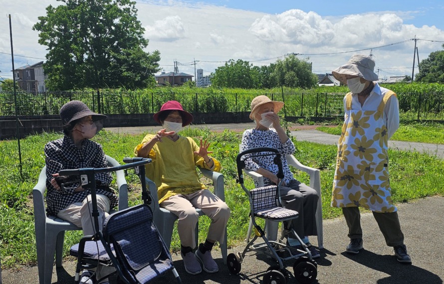 梅雨の晴れ間の園庭でご利用者がお話しされています