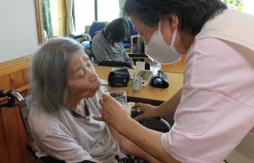 薬の飲まれているご利用者と介助するスタッフです