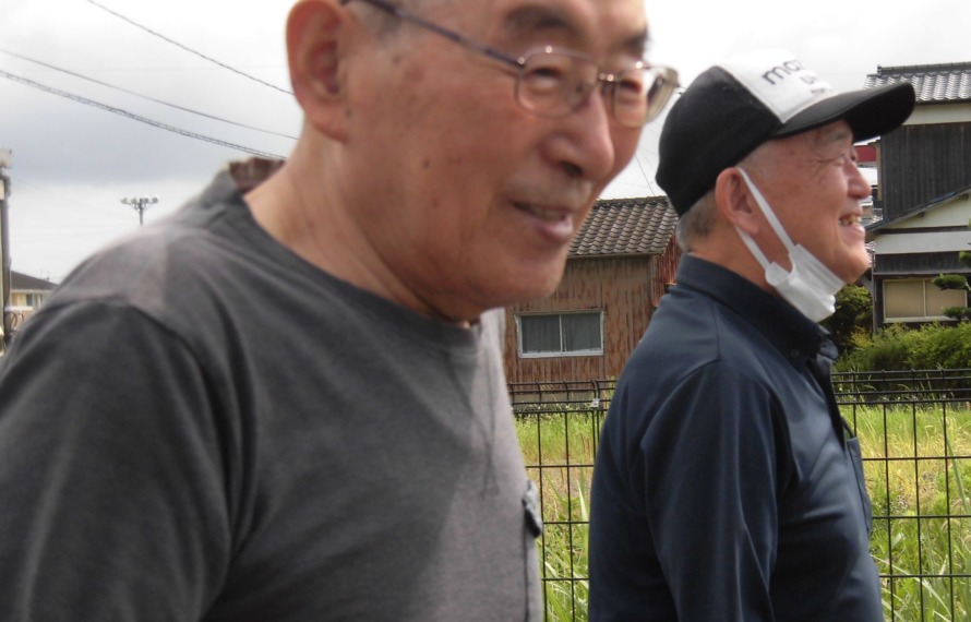 園庭を歩かれる男性ご利用者と付き添うスタッフです