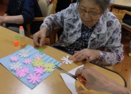 切ってある花の色紙を用紙に貼られるご利用者