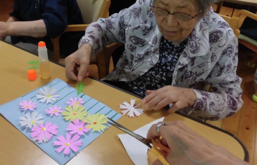 切ってある花の色紙を用紙に貼られるご利用者