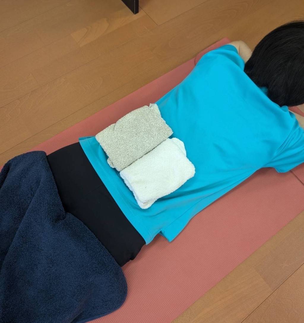 うつぶせになり、こんにゃくで腎臓を温めている