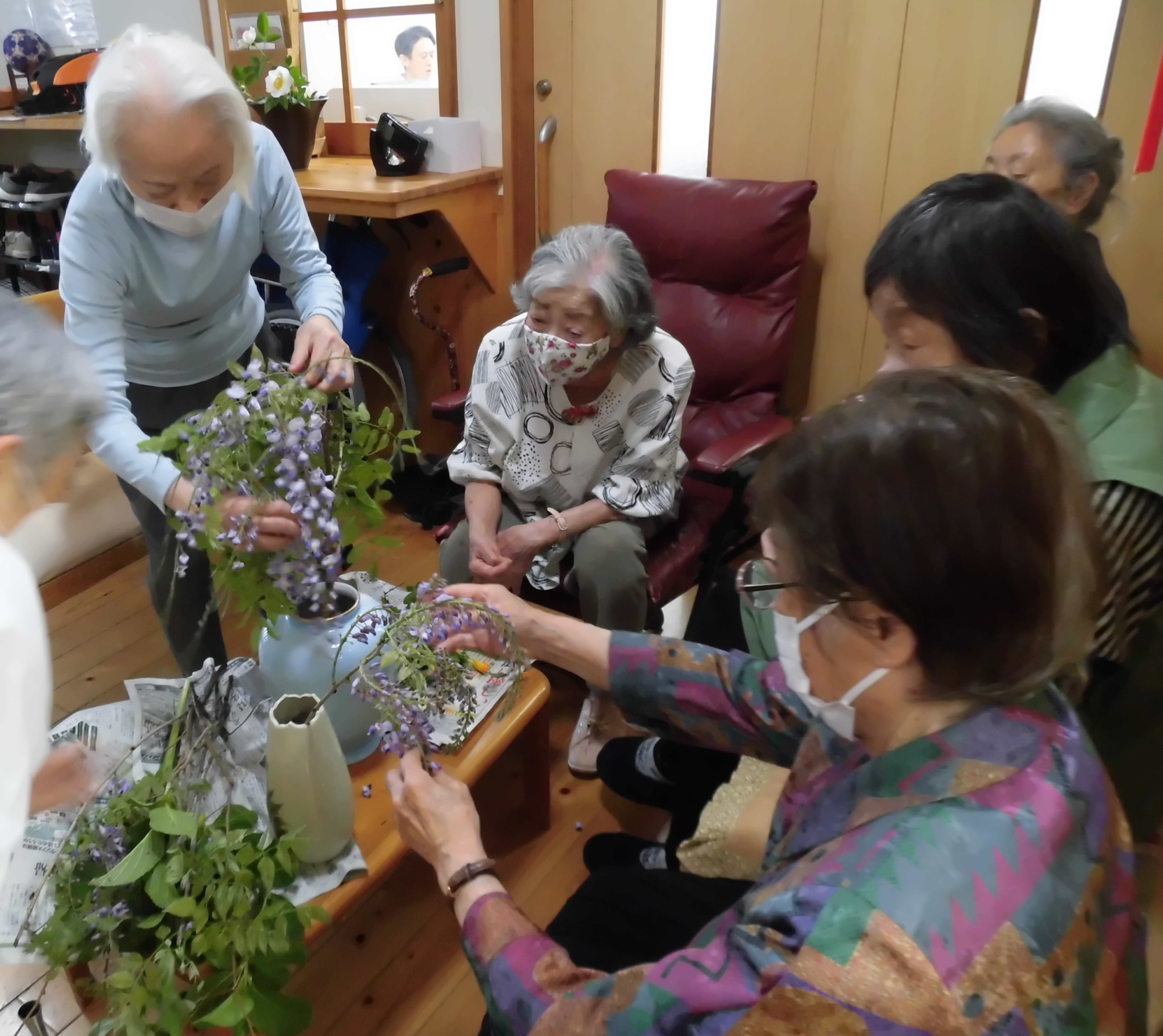 藤の花を花瓶に状背の利用者が活けられています