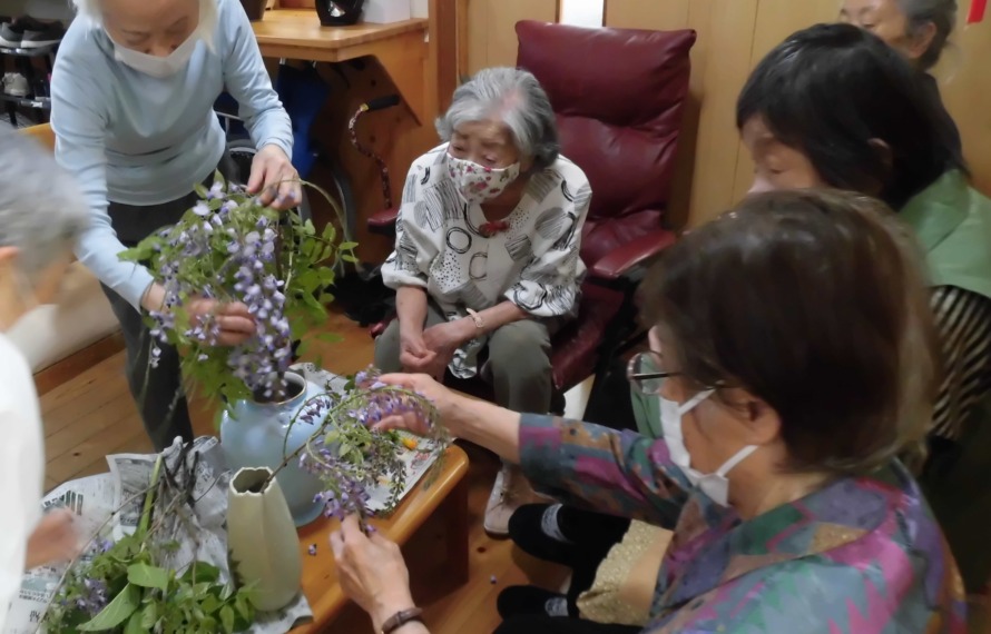 藤の花を花瓶に状背の利用者が活けられています