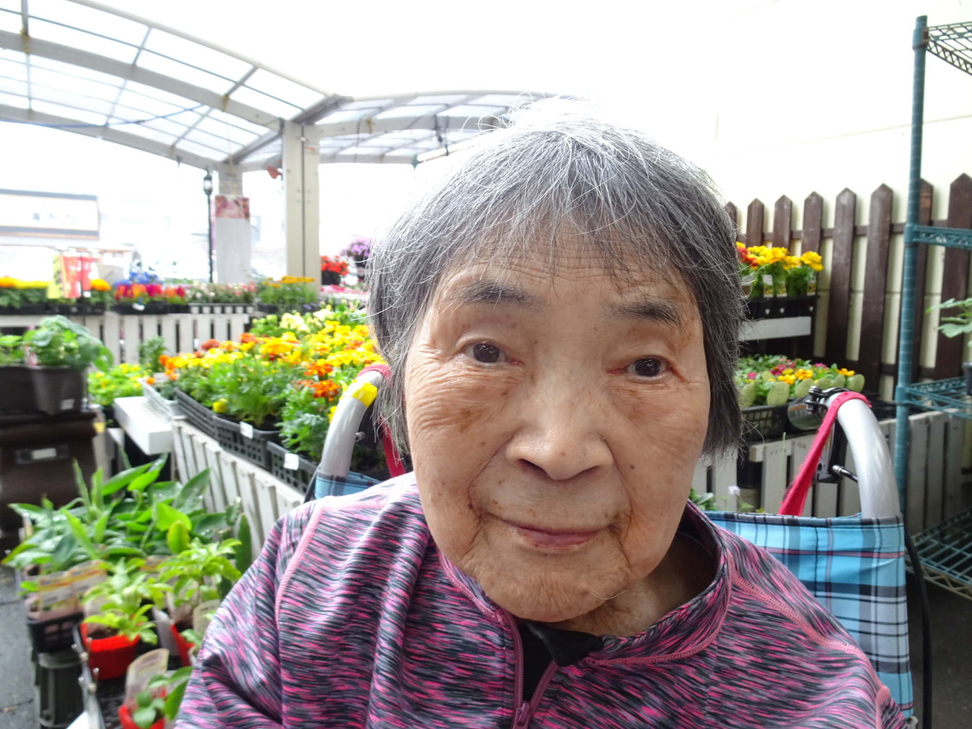 お花の前で笑顔で写る利用者さんの写真