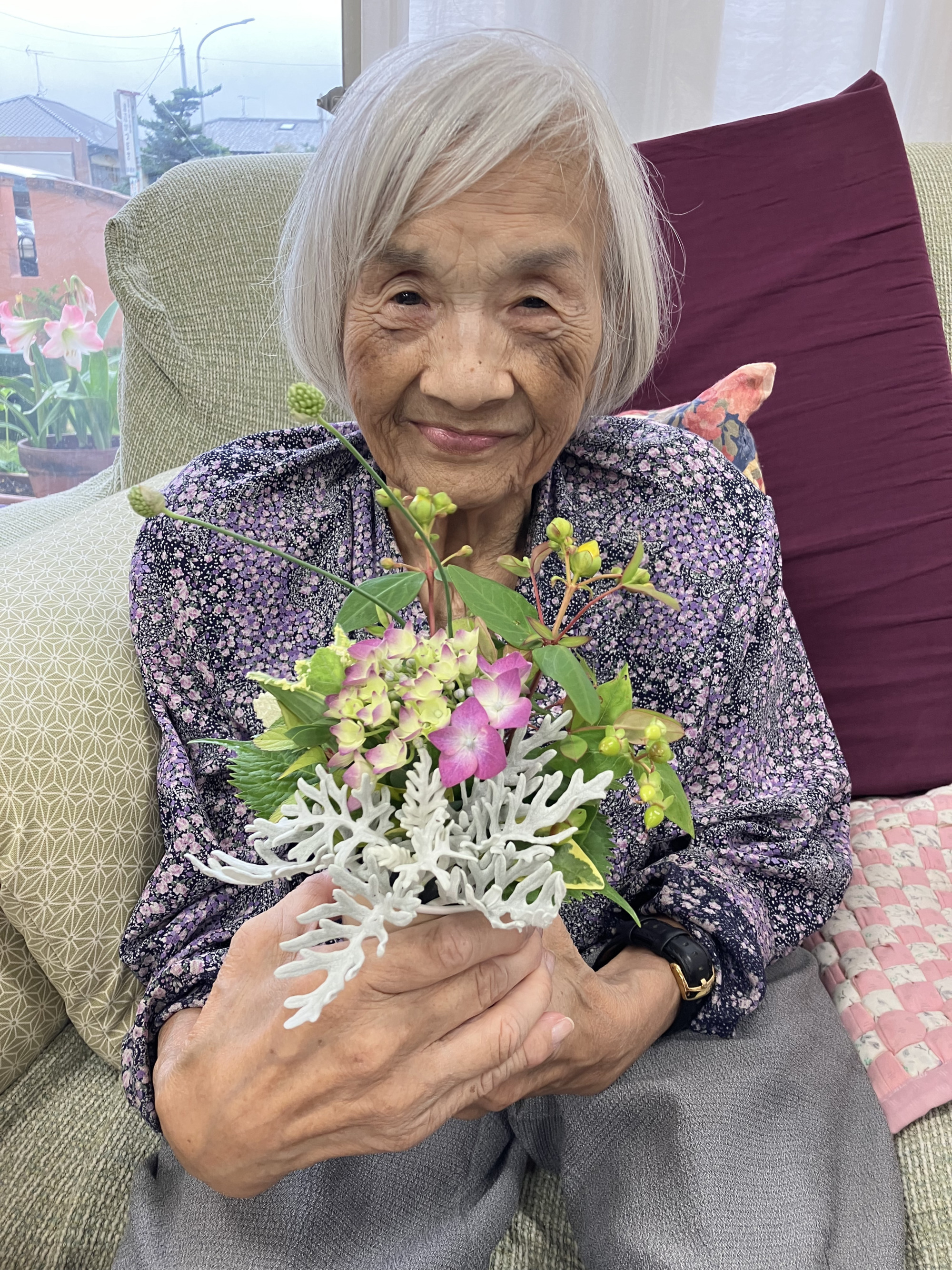 完成したフラワーアレンジメントを手にして笑顔の利用者さんの写真