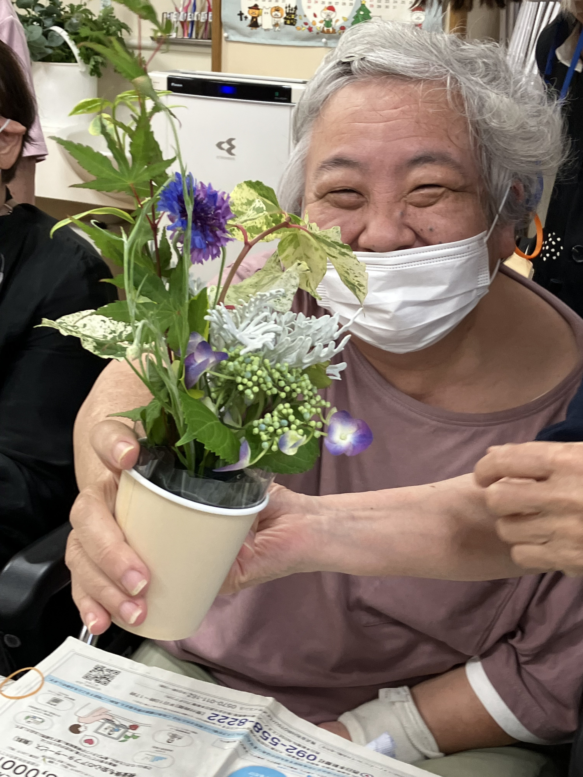 完成したフラワーアレンジメントを手にして笑顔の利用者さんの写真