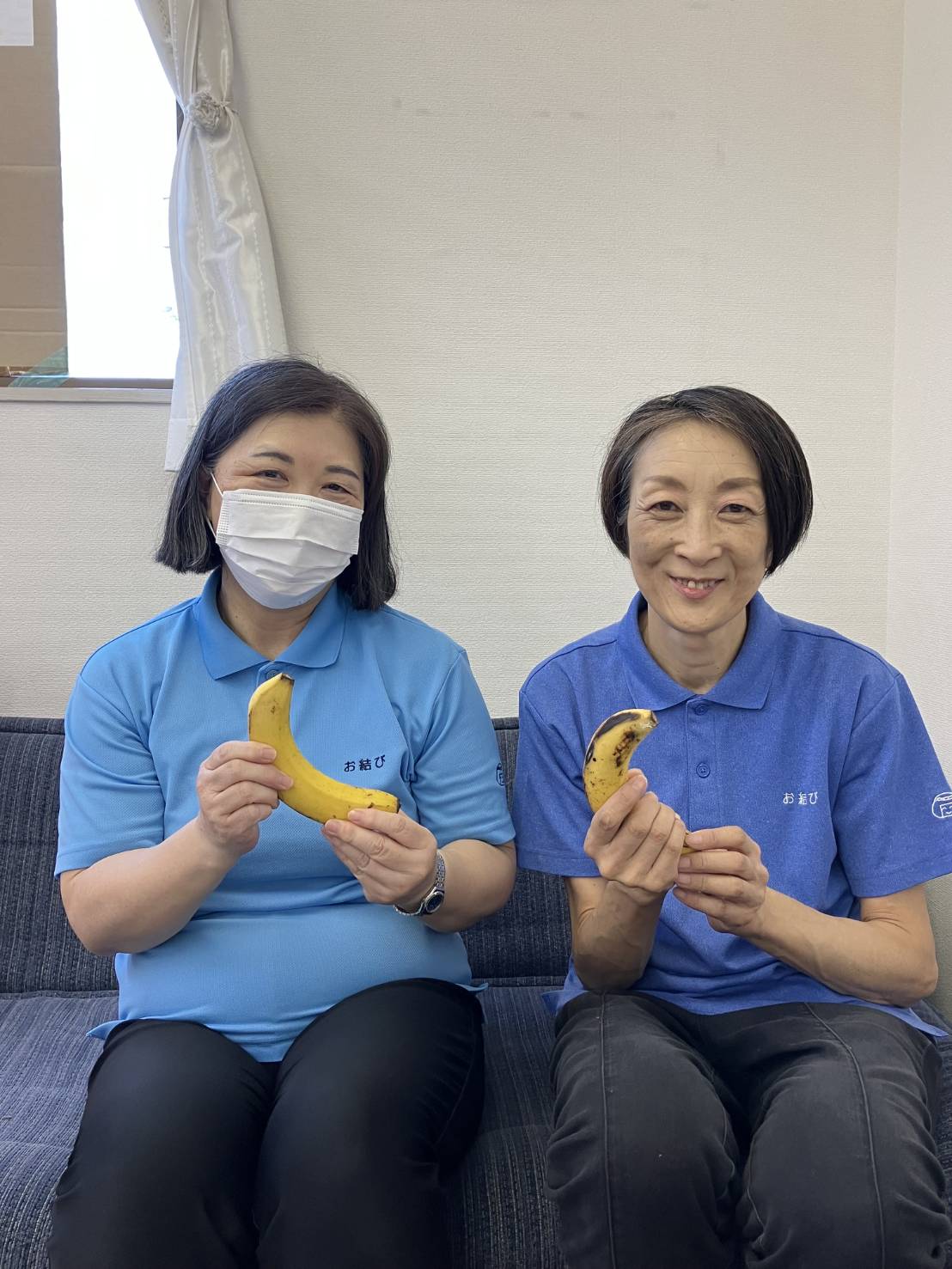 ワーカー2人が笑顔でバナナを1本ずつ持っている