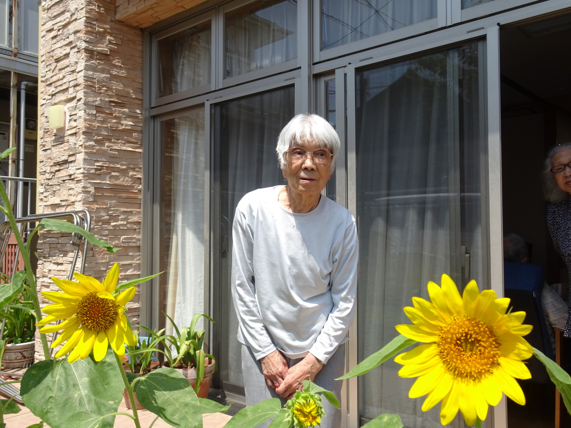 ひまわりと一緒に写真を撮る利用者さん
