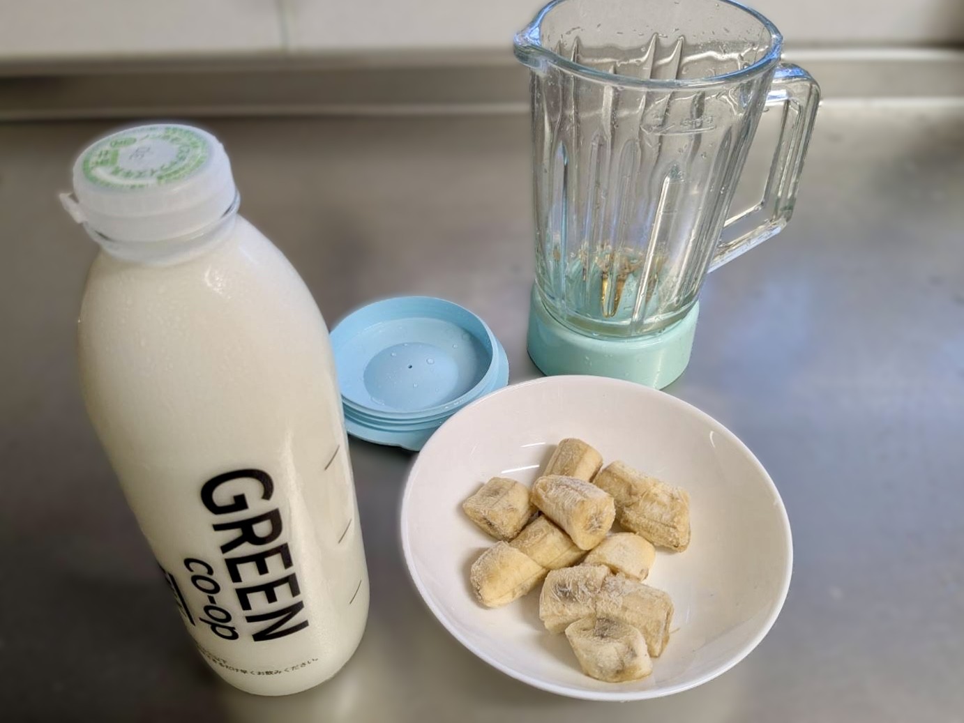びん牛乳とカットバナナ、ミキサーの写真