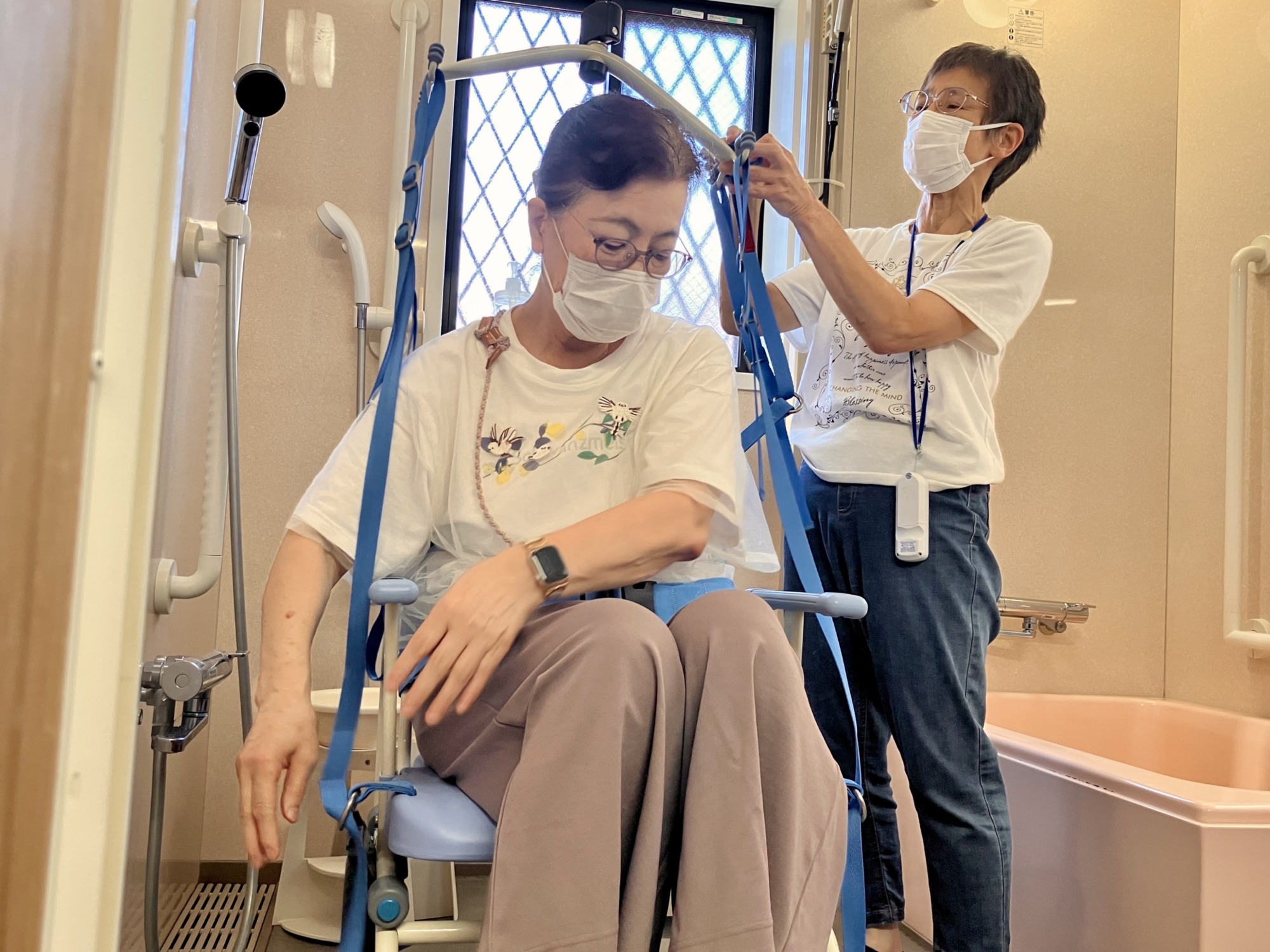 ご利用者に専用の椅子に乗ってもらい、リフトを取り付ける様子