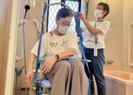 ご利用者に専用の椅子に乗ってもらい、リフトを取り付ける様子