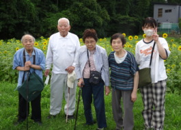 ひまわり畑の前で撮った利用者さんとワーカーの集合写真
