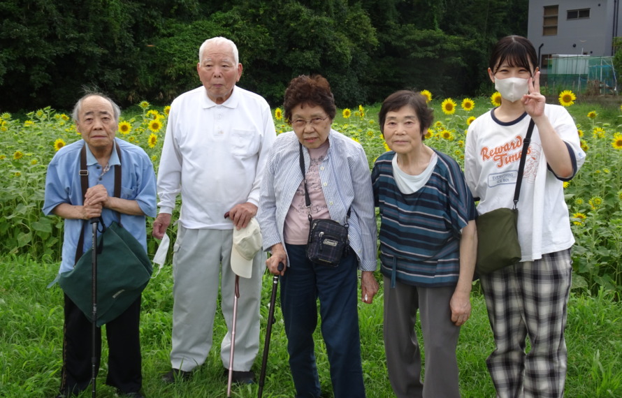 ひまわり畑の前で撮った利用者さんとワーカーの集合写真