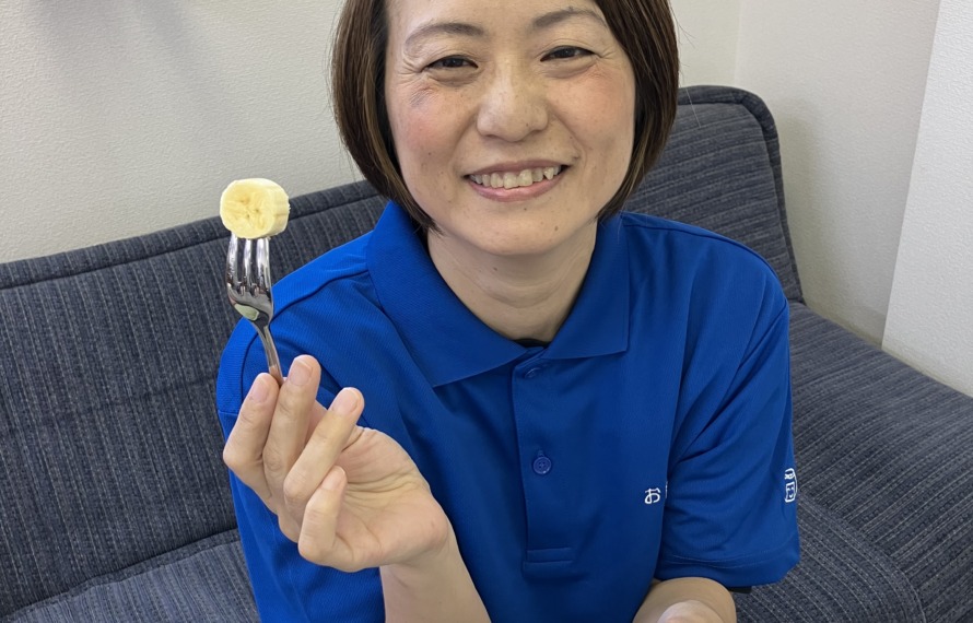 ワーカーが塩バナナを食べようとバナナをフォークにさし、笑顔で持っている
