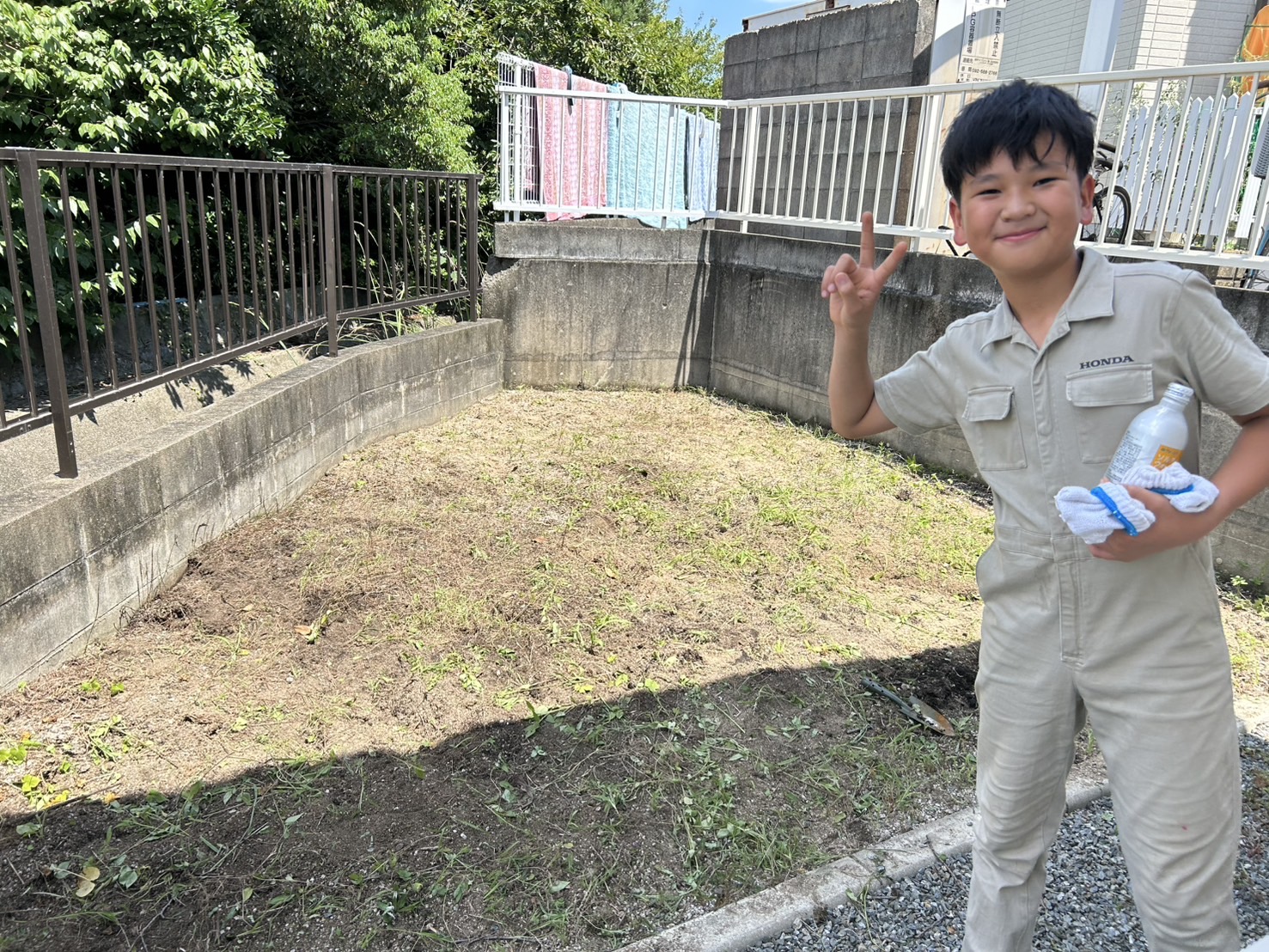 草取り後のきれいになった裏庭でピースのポーズを取って写る子ども