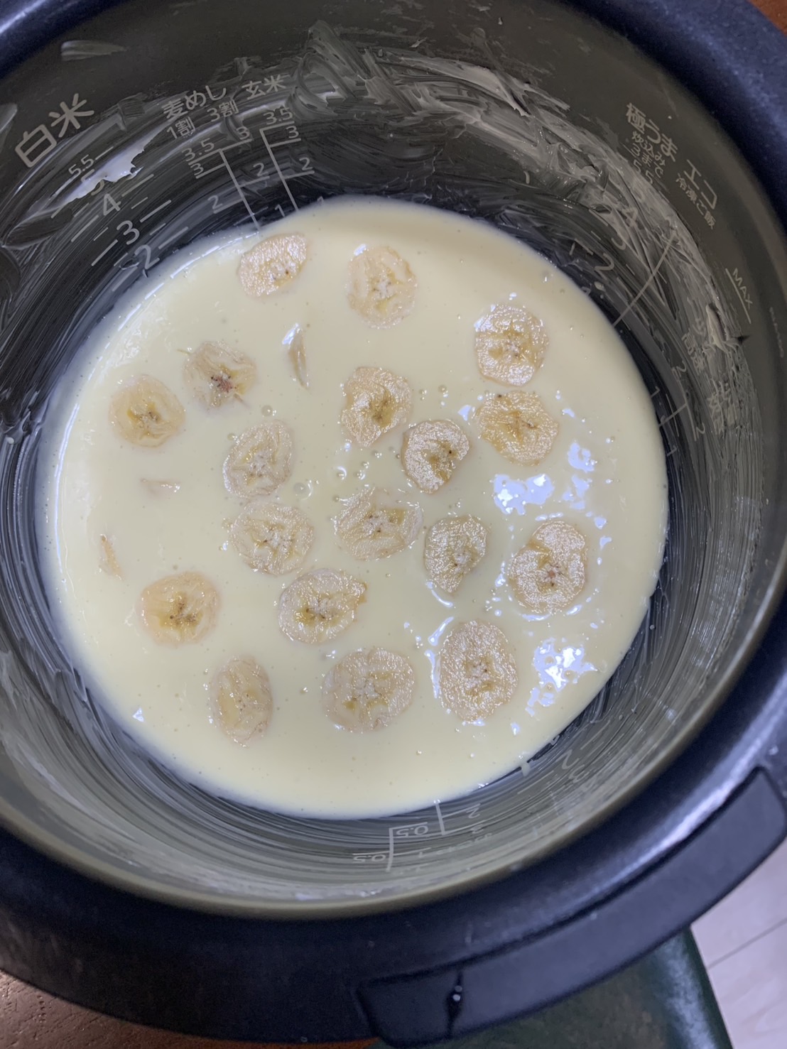 バターを塗った炊飯器にケーキの生地を入れ、バナナを並べたところ