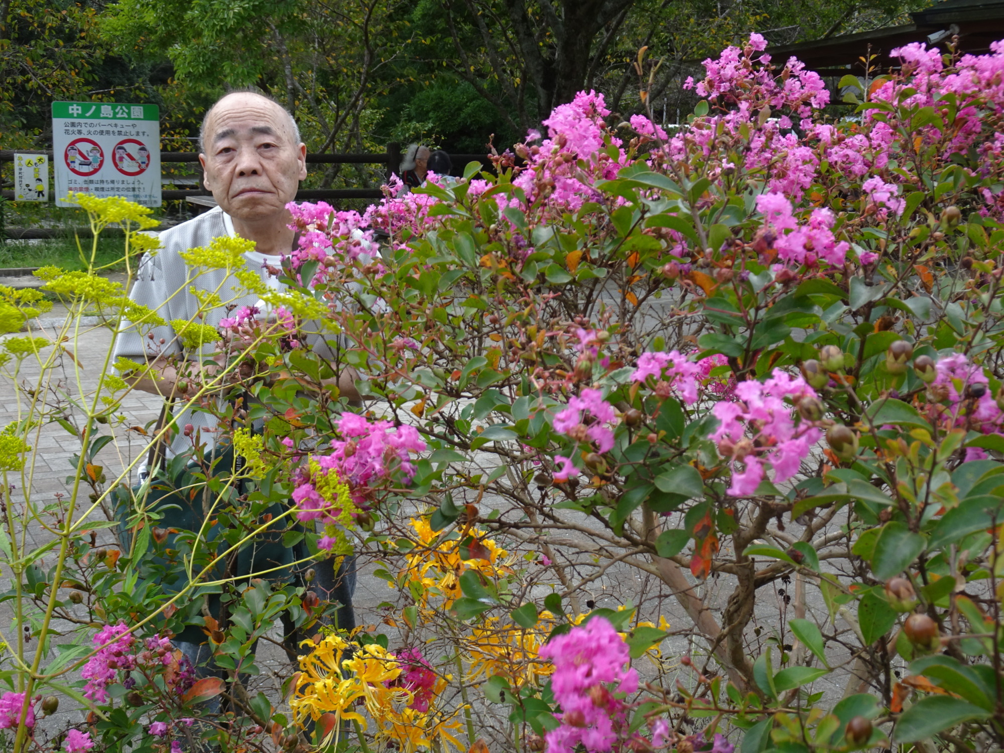 ピンクや黄色の花と写る利用者さん