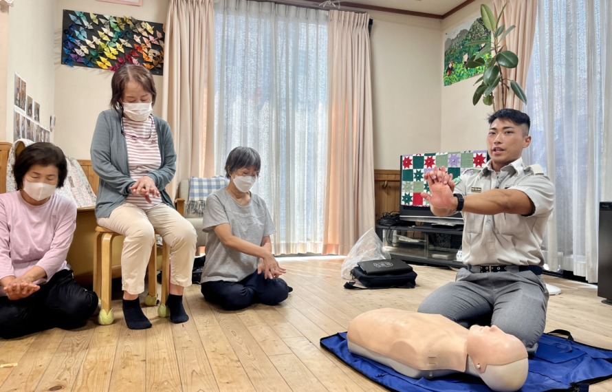 救急救命士から心臓マッサージの時の手の組み方を指導してもらっている様子