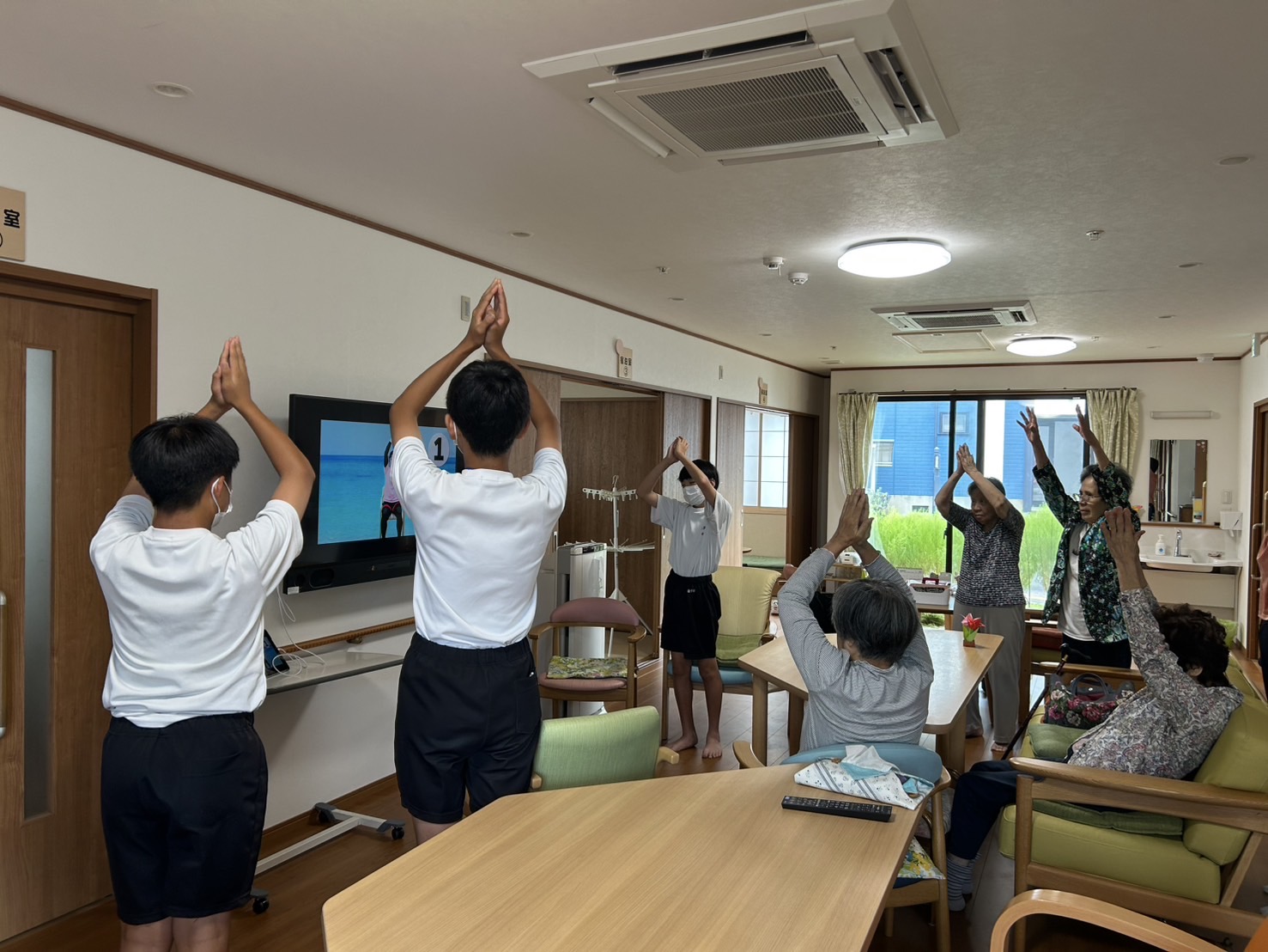 一緒に体操をする利用者さんと中学生