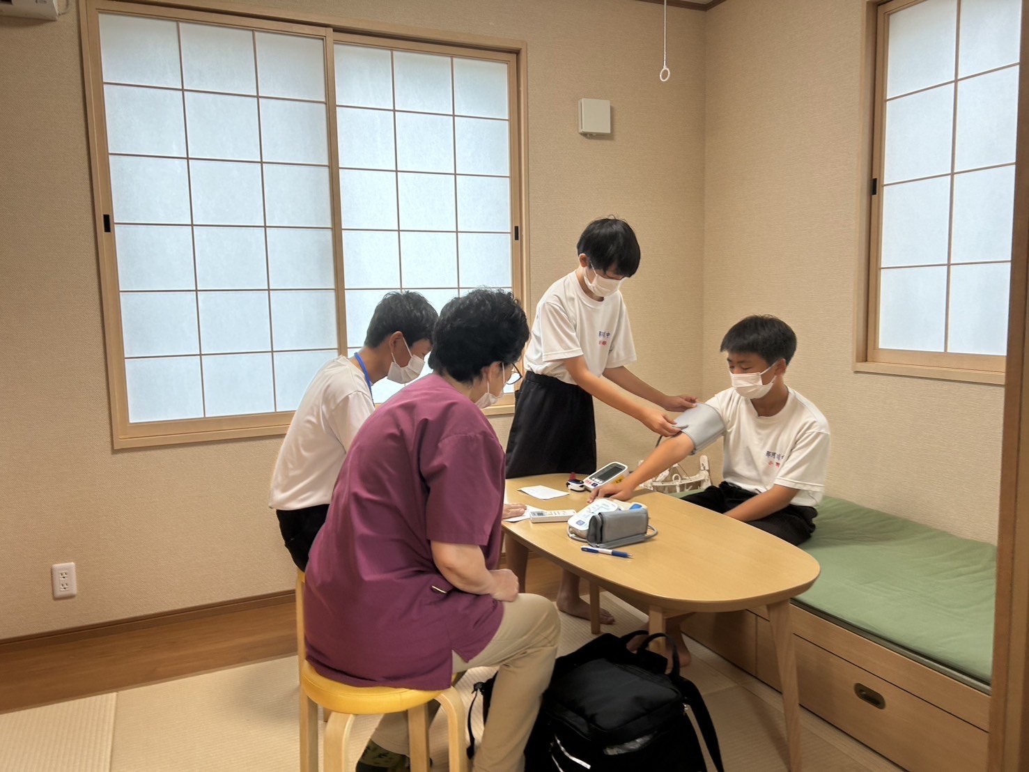 ワーカーから血圧の測り方を教わる中学生