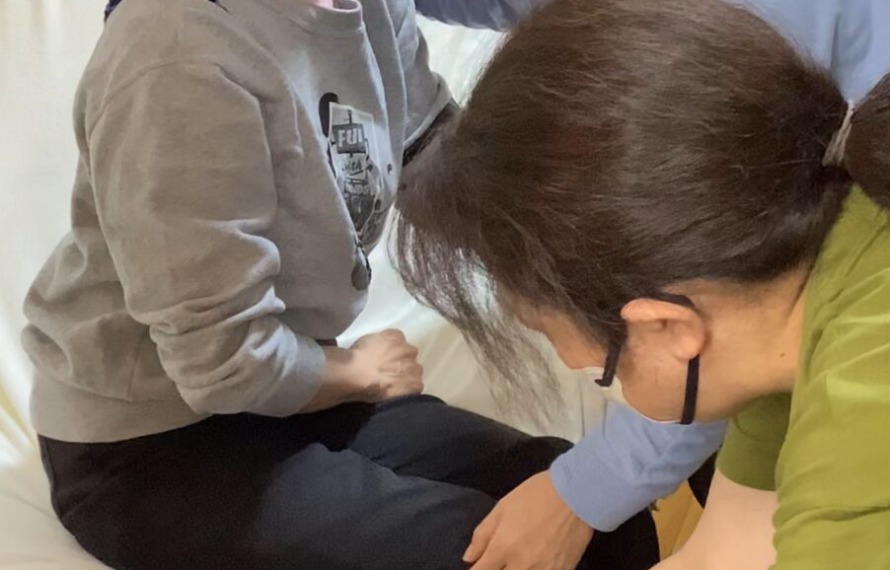 スライディングボードを使ってベッドから車いすへ移乗している様子