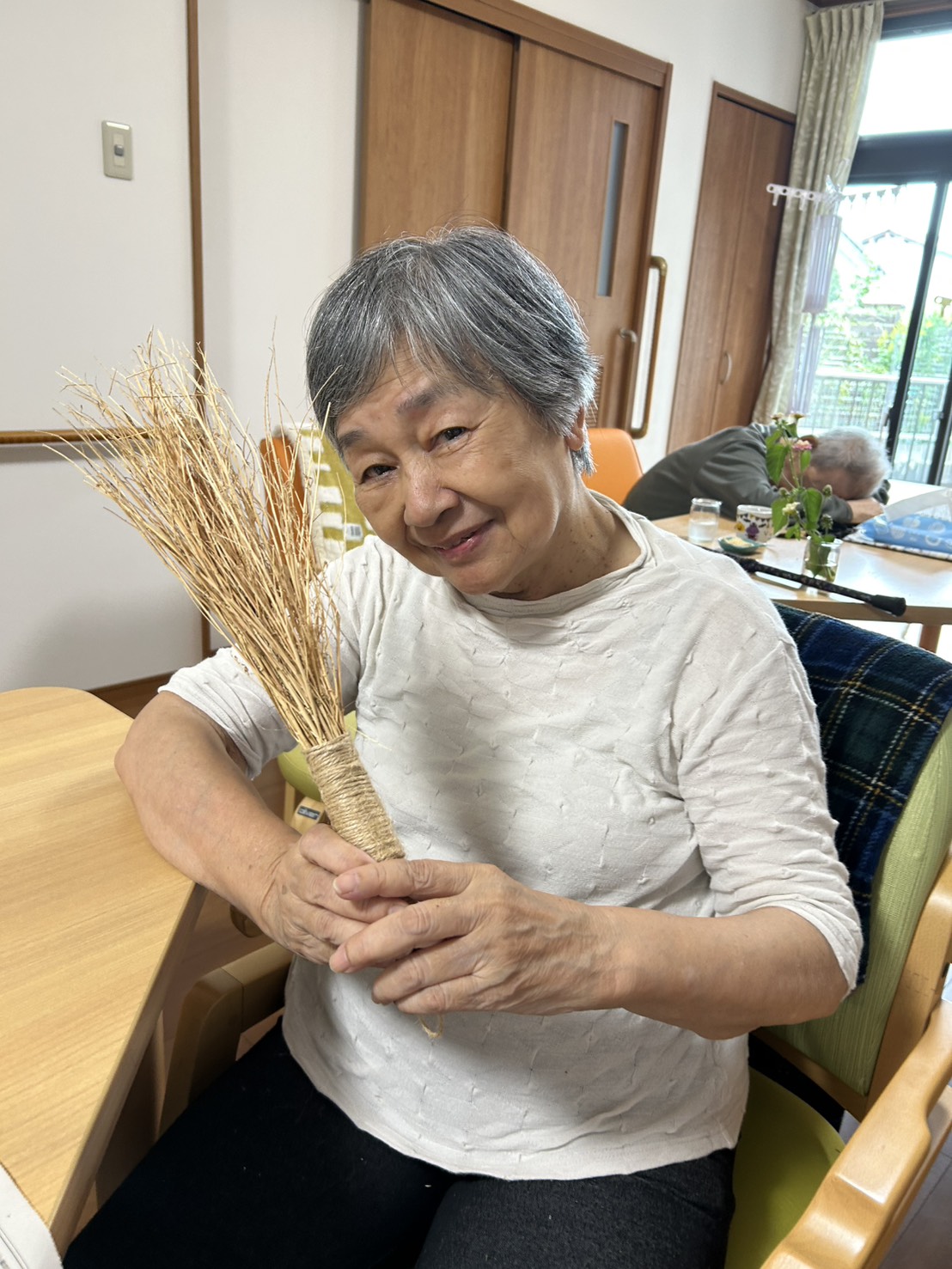 作ったホウキを手に笑顔の利用者さん