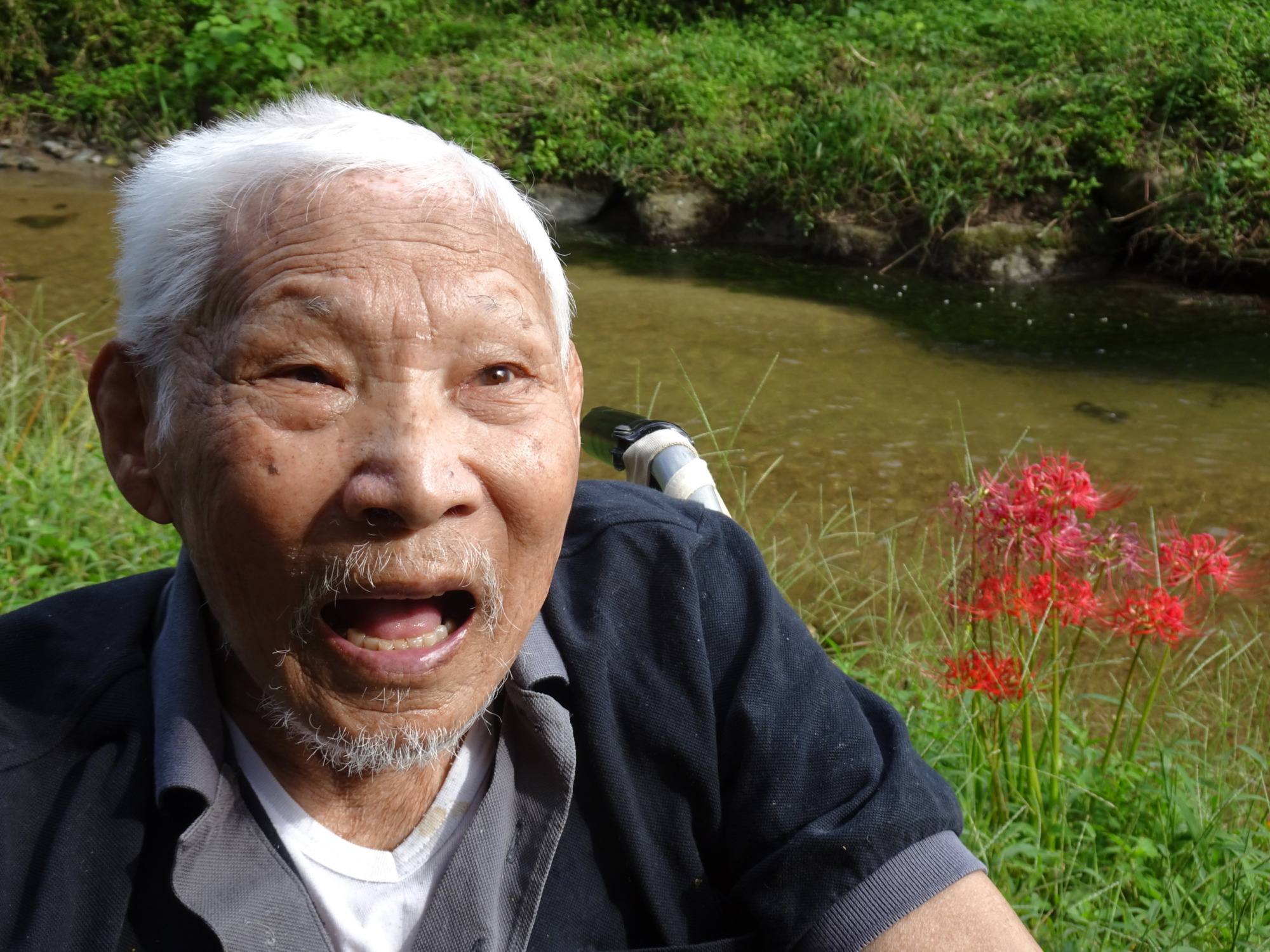 彼岸花を背景に写る男性入所者さん