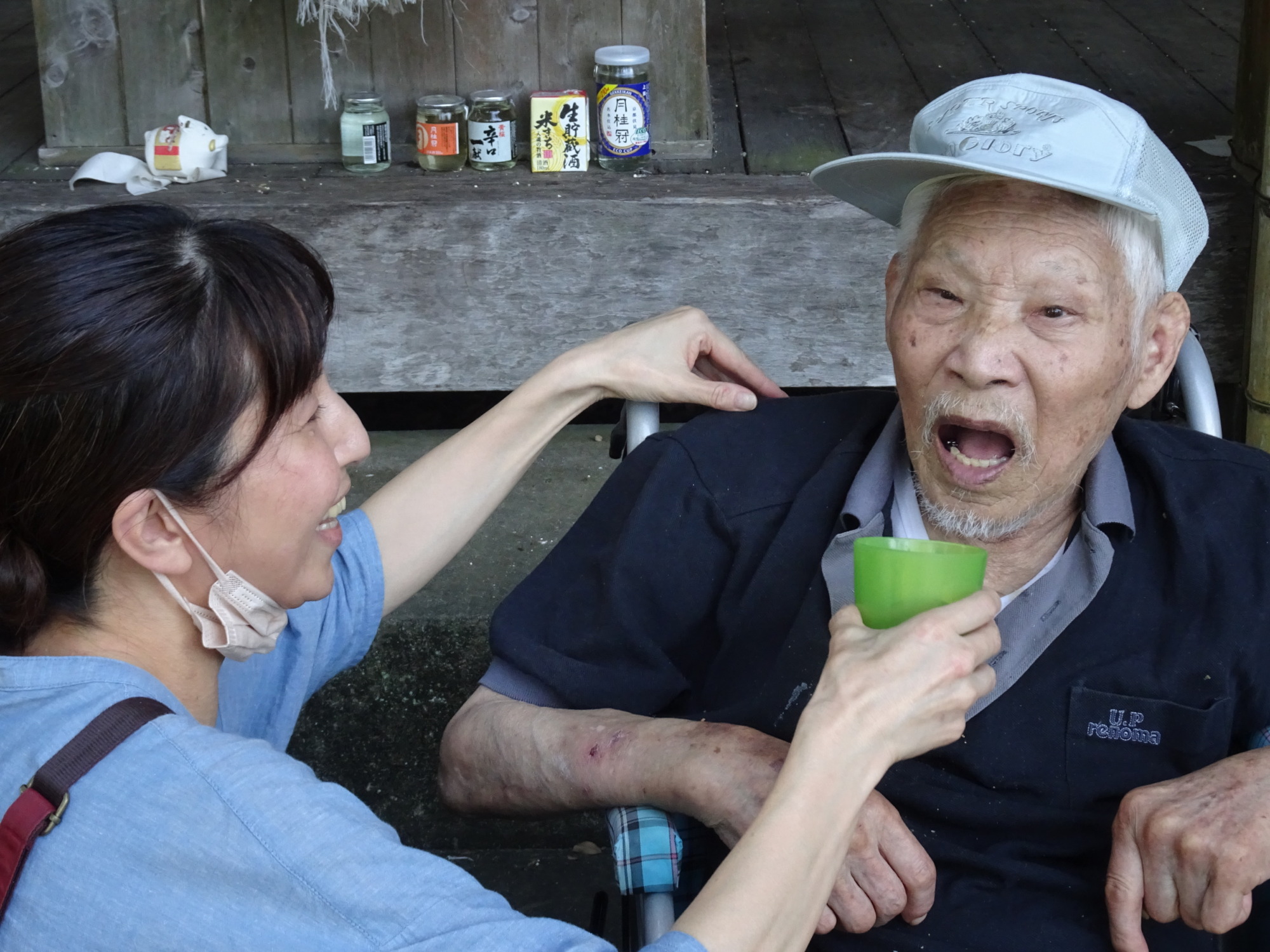 お茶を飲む利用者さんと介助するワーカー