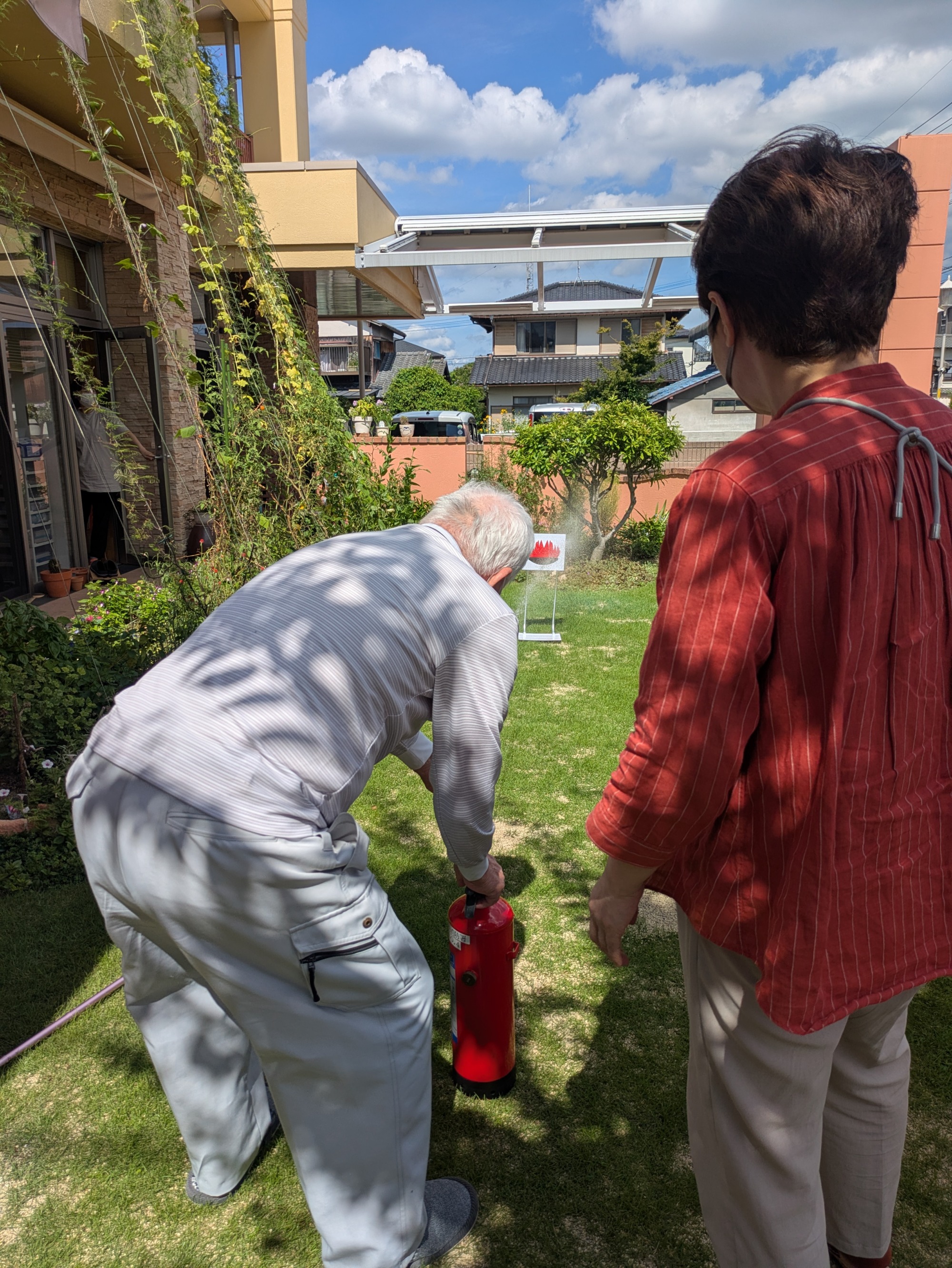 消火器の水を噴射して炎のパネルに命中させる利用者さん