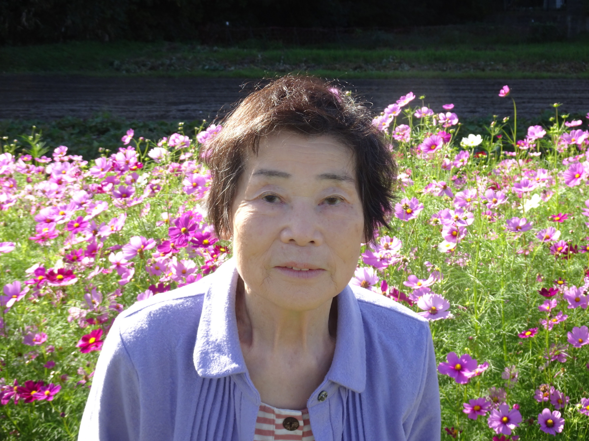 コスモス畑の前で笑顔を見せる利用者さん
