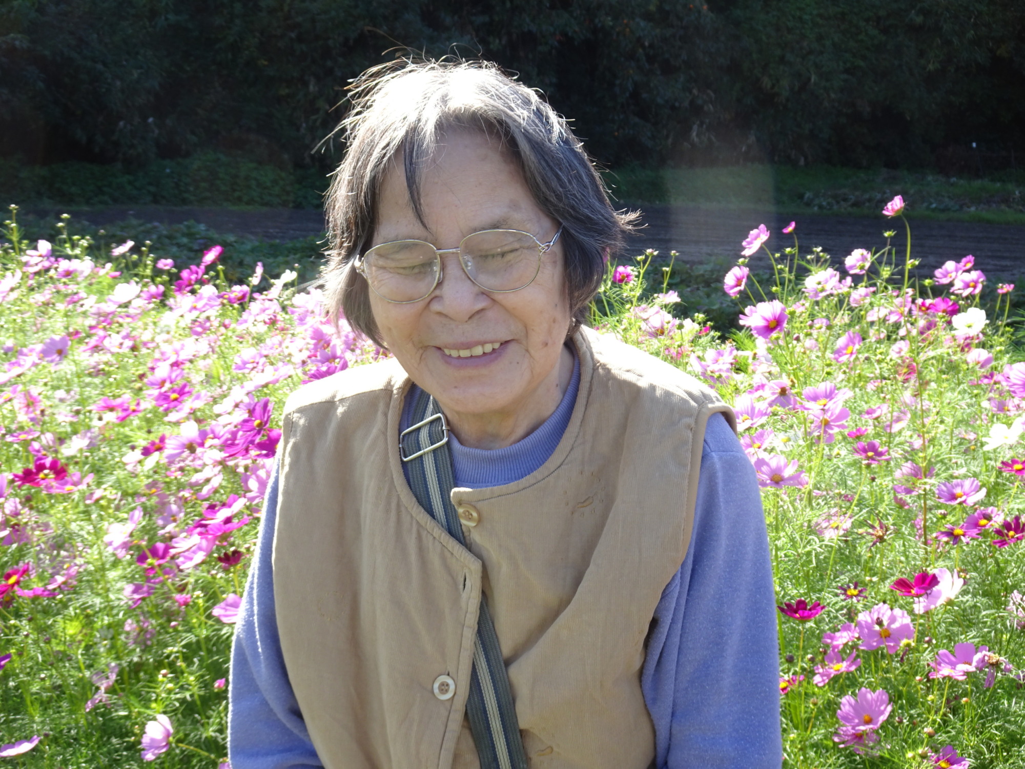 コスモス畑の前で素敵な笑顔を見せる利用者さん