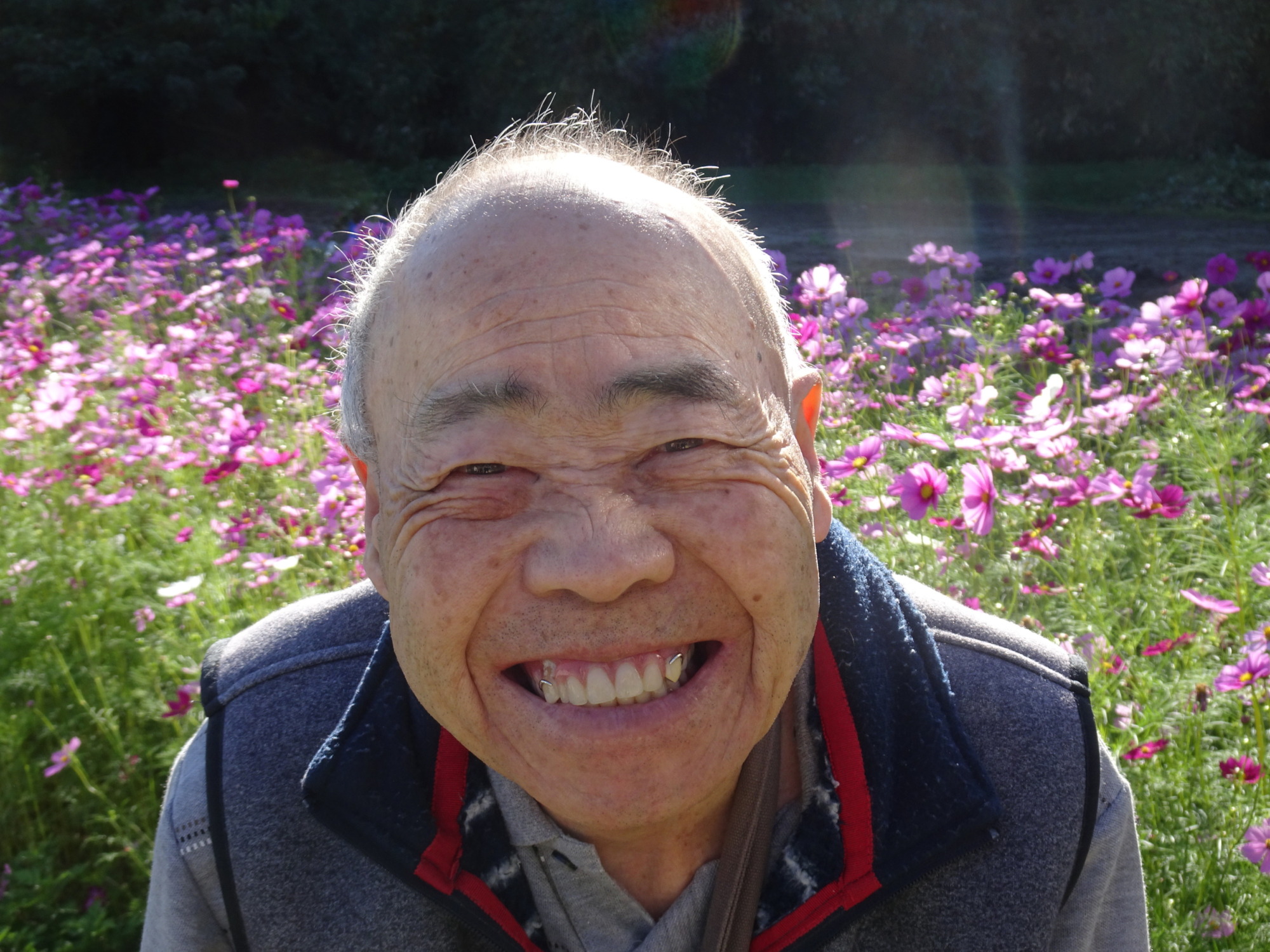 コスモス畑の前で素敵な笑顔を見せる利用者さん