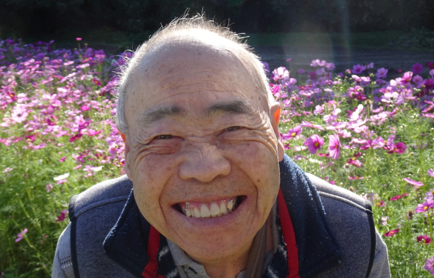 コスモス畑の前で素敵な笑顔を見せる利用者さん