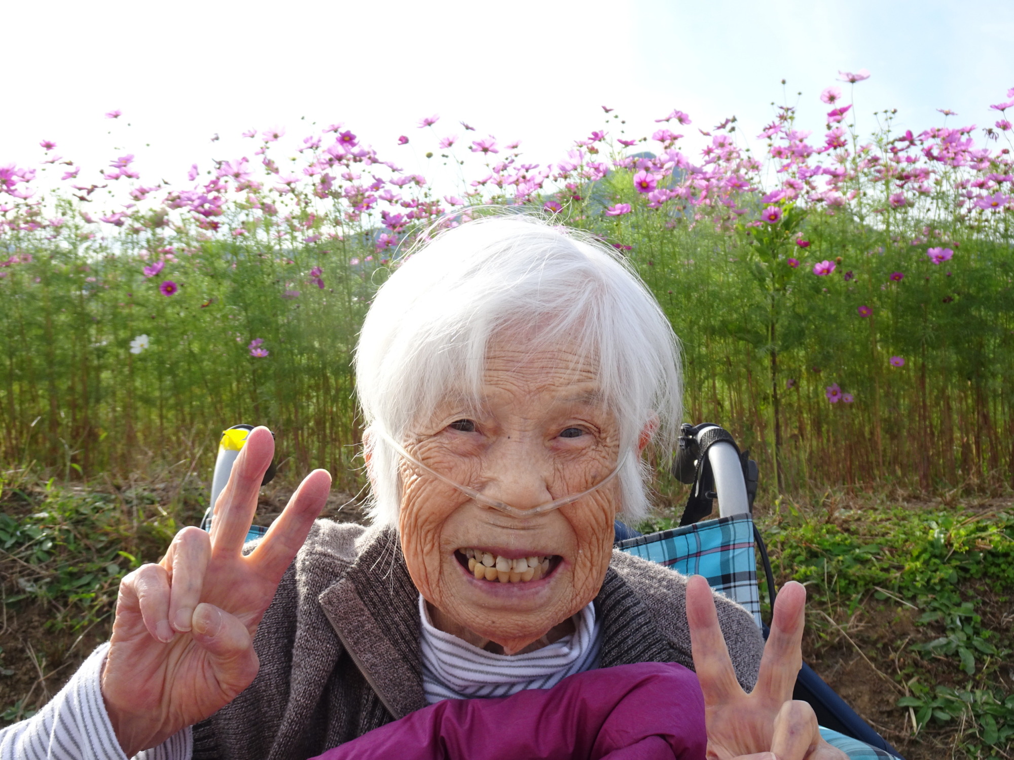 コスモス畑の前で素敵な笑顔を見せる利用者さん