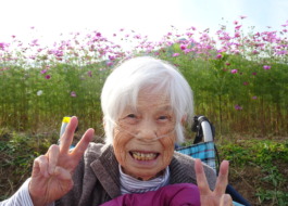 コスモス畑の前で素敵な笑顔を見せる利用者さん