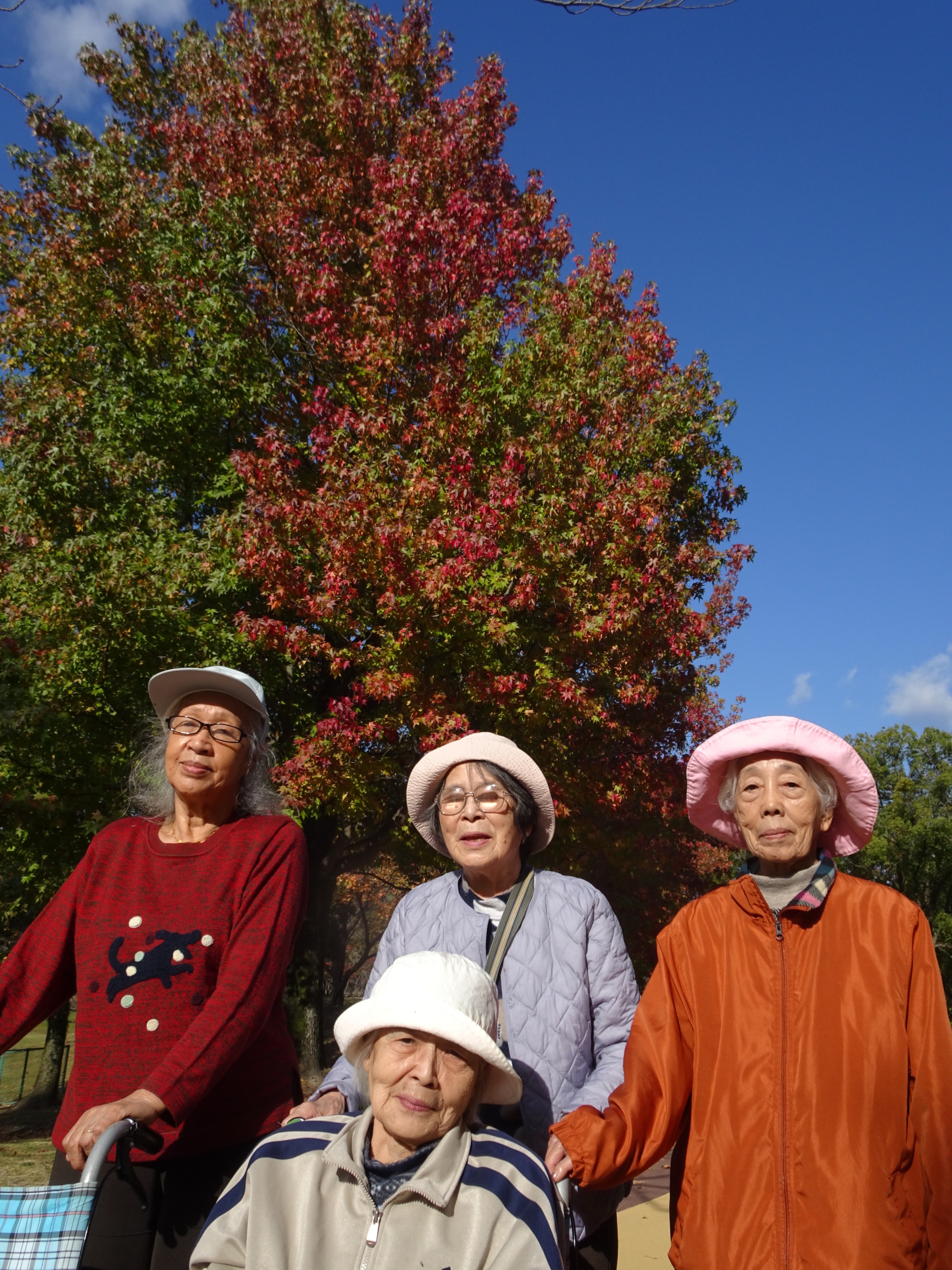 紅葉をバックに撮った利用者さんたちの写真