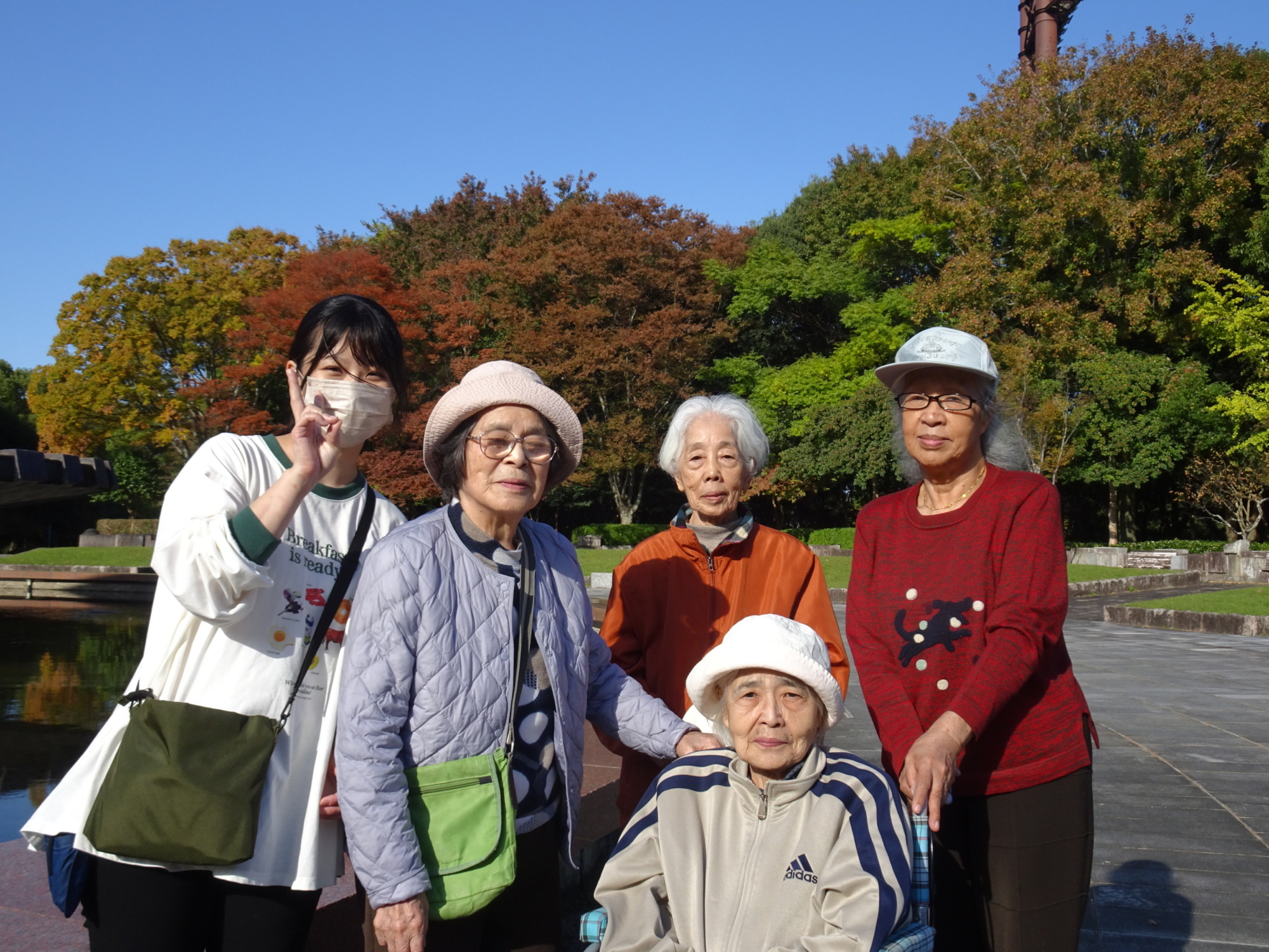 春日公園内で紅葉をバックに撮った利用者さんたちとワーカーの写真