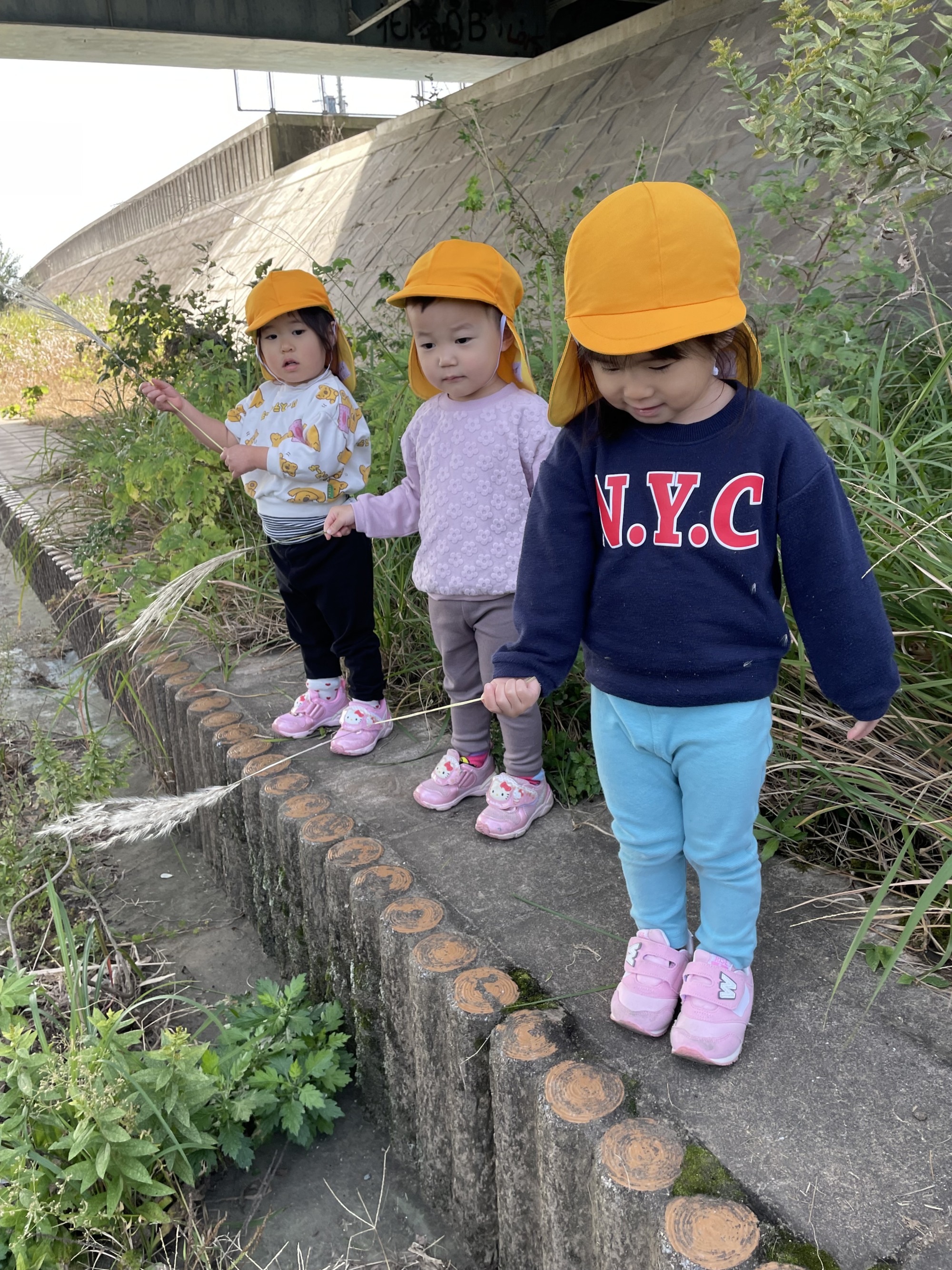 先生にとってもらったススキの葉っぱを持って3人並んでいる様子