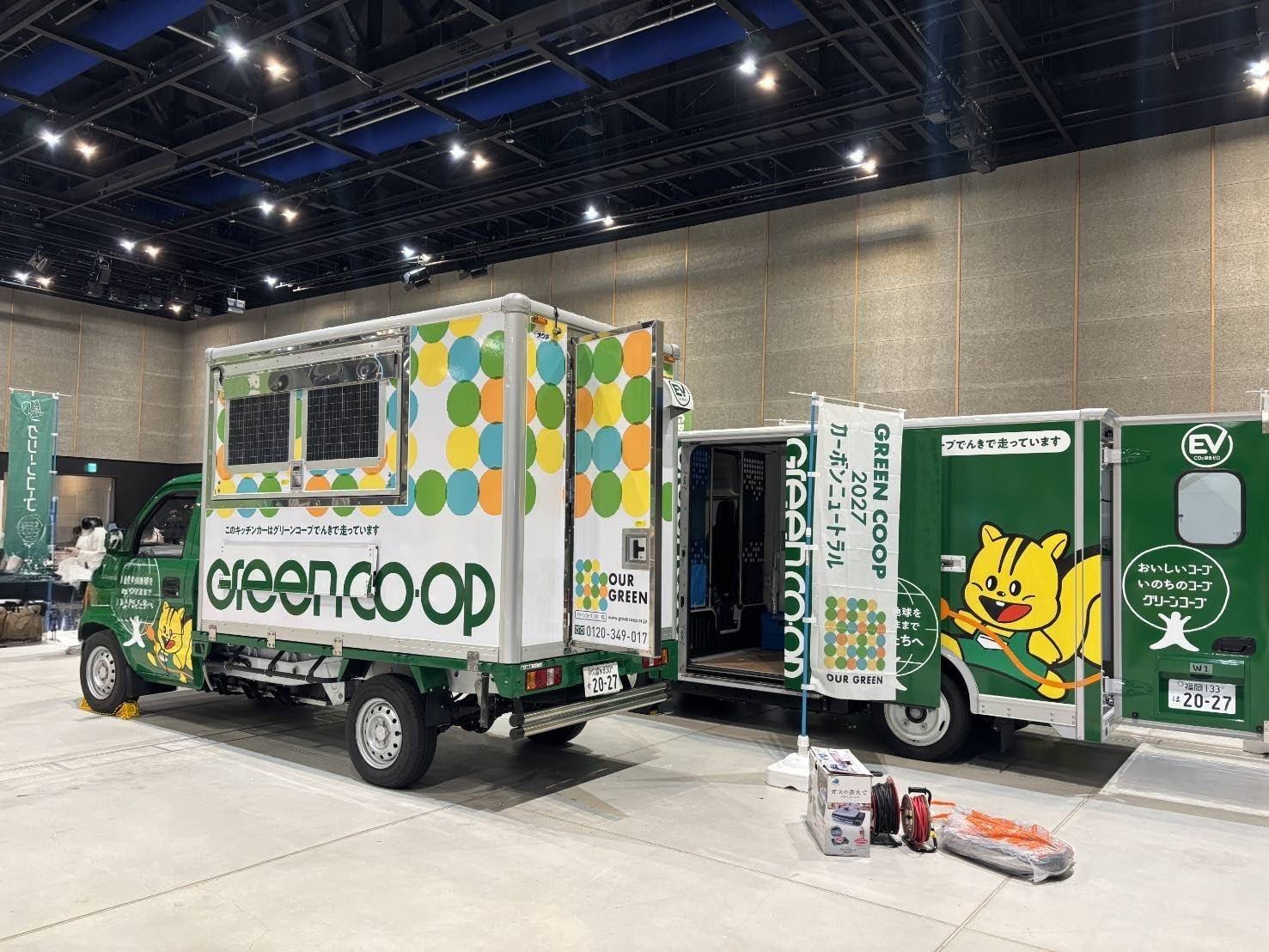 カーボンニュートラルのグリーンコープのキッチンカーと配送トラックが一台ずつ並んでいる