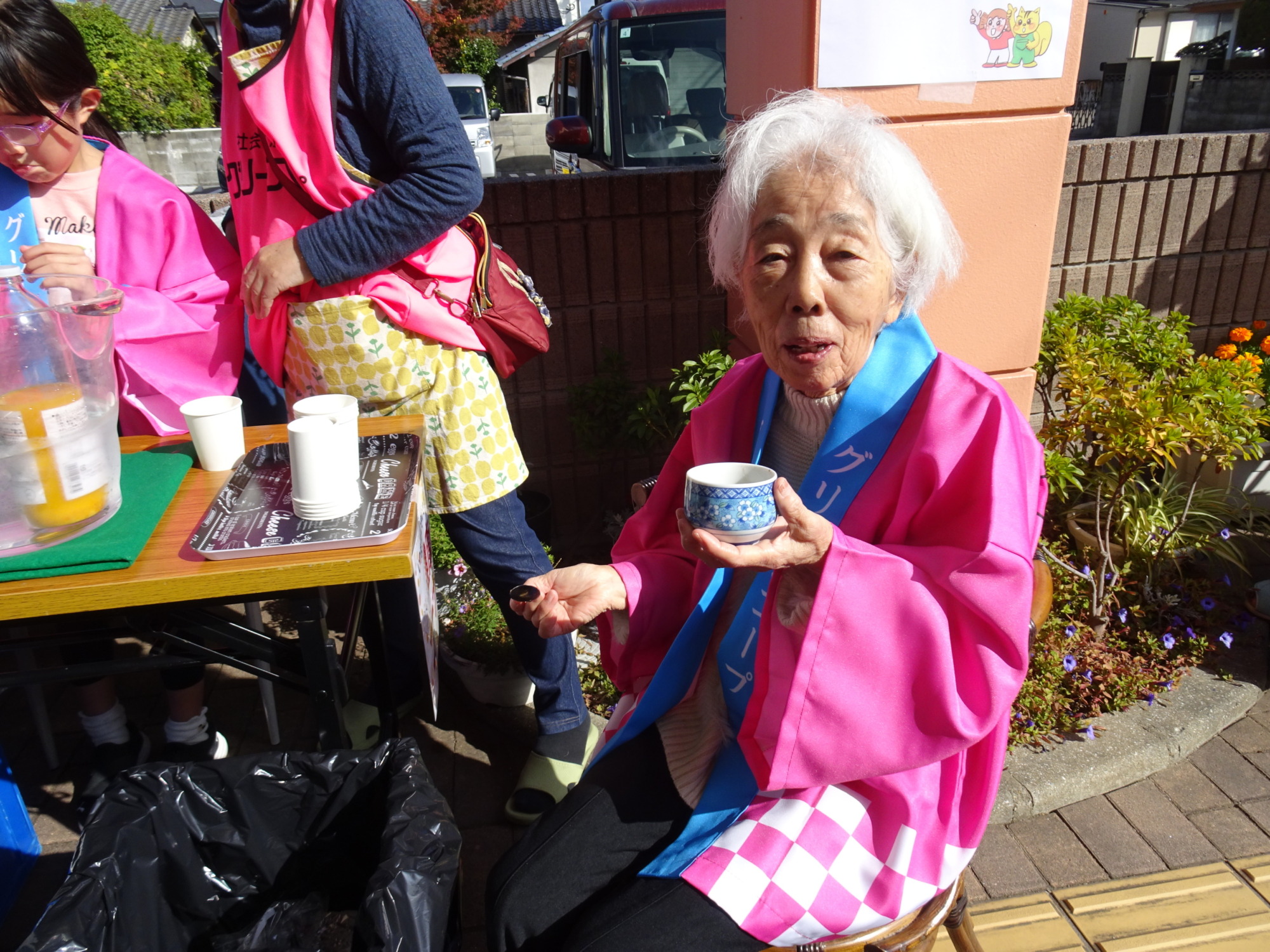 ピンクの法被を着てぜんざいを食べる利用者さん