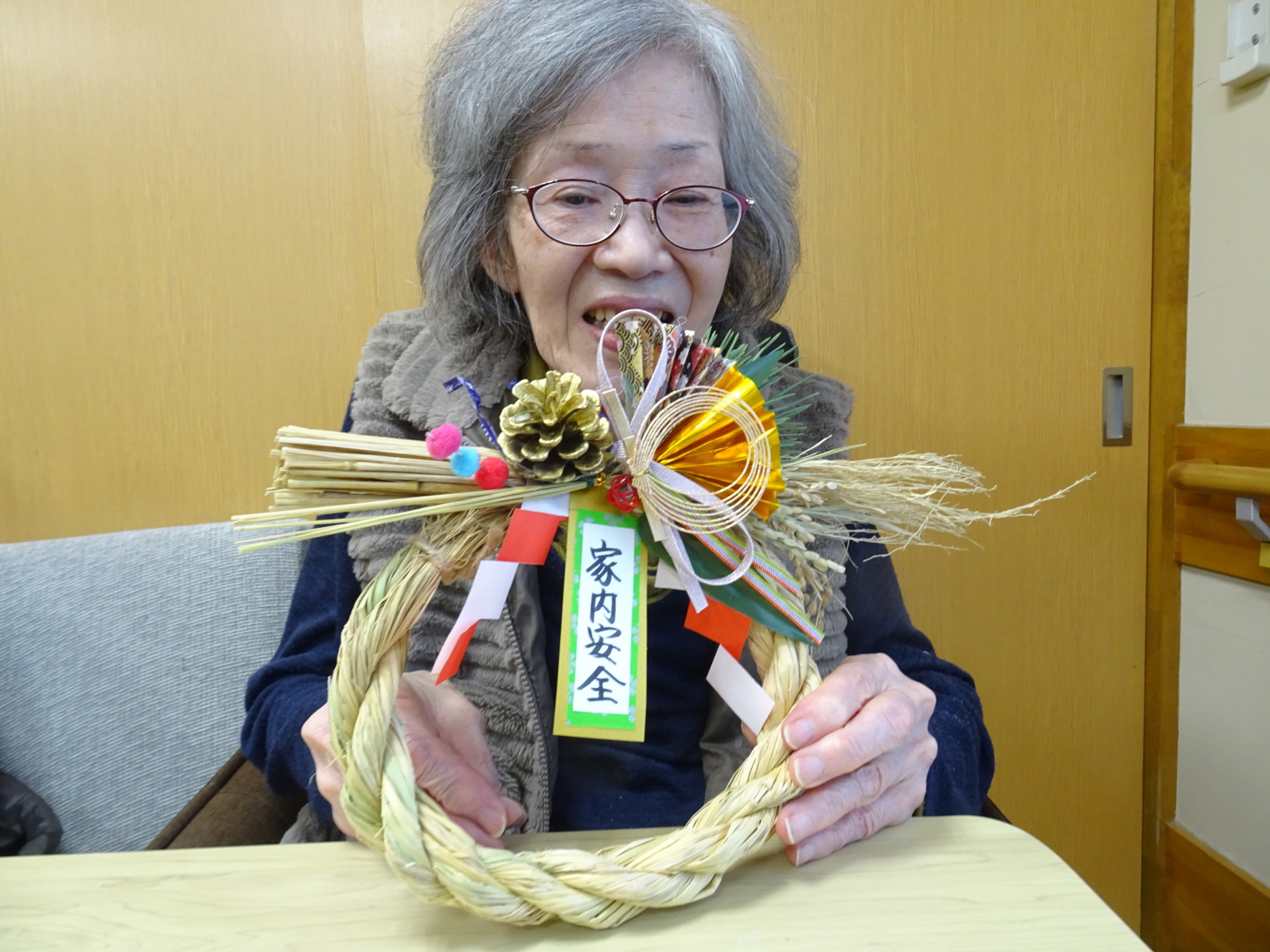 完成したしめ縄を持って笑顔で写る利用者さん