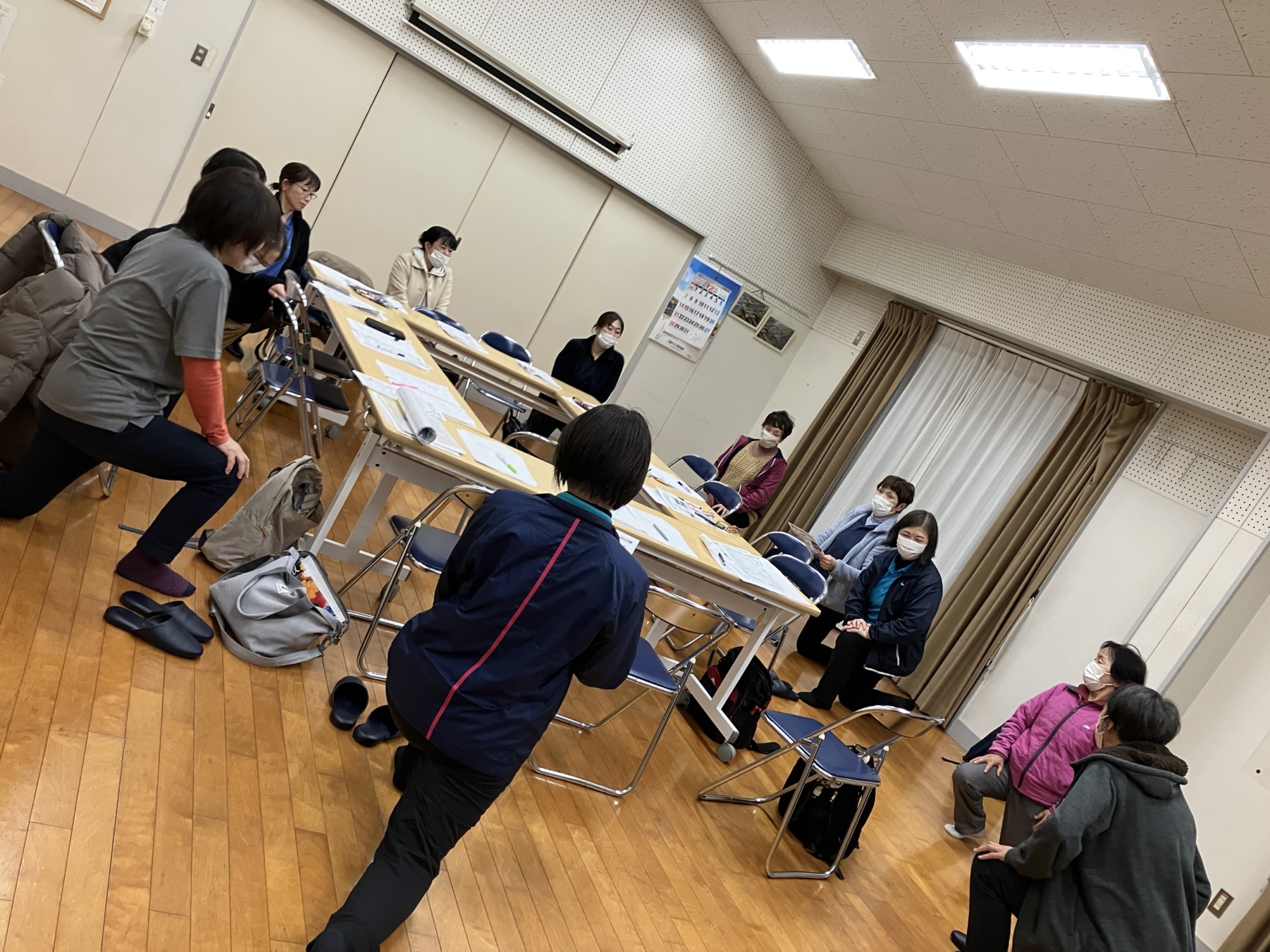 職場会議でみんなで片膝立ちの姿勢で腸腰筋ストレッチをしている