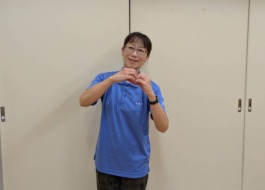 新しく入職したワーカーが両手でハートマークを作って笑顔で微笑んでいる。