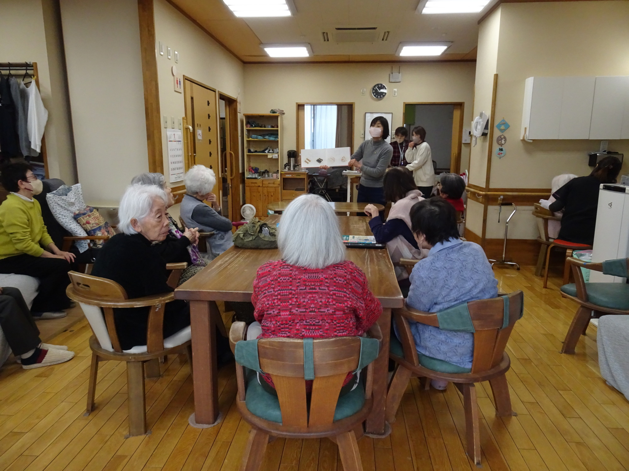 絵本を読み聞かせるボランティアの方とそれを聴く利用者さんたち