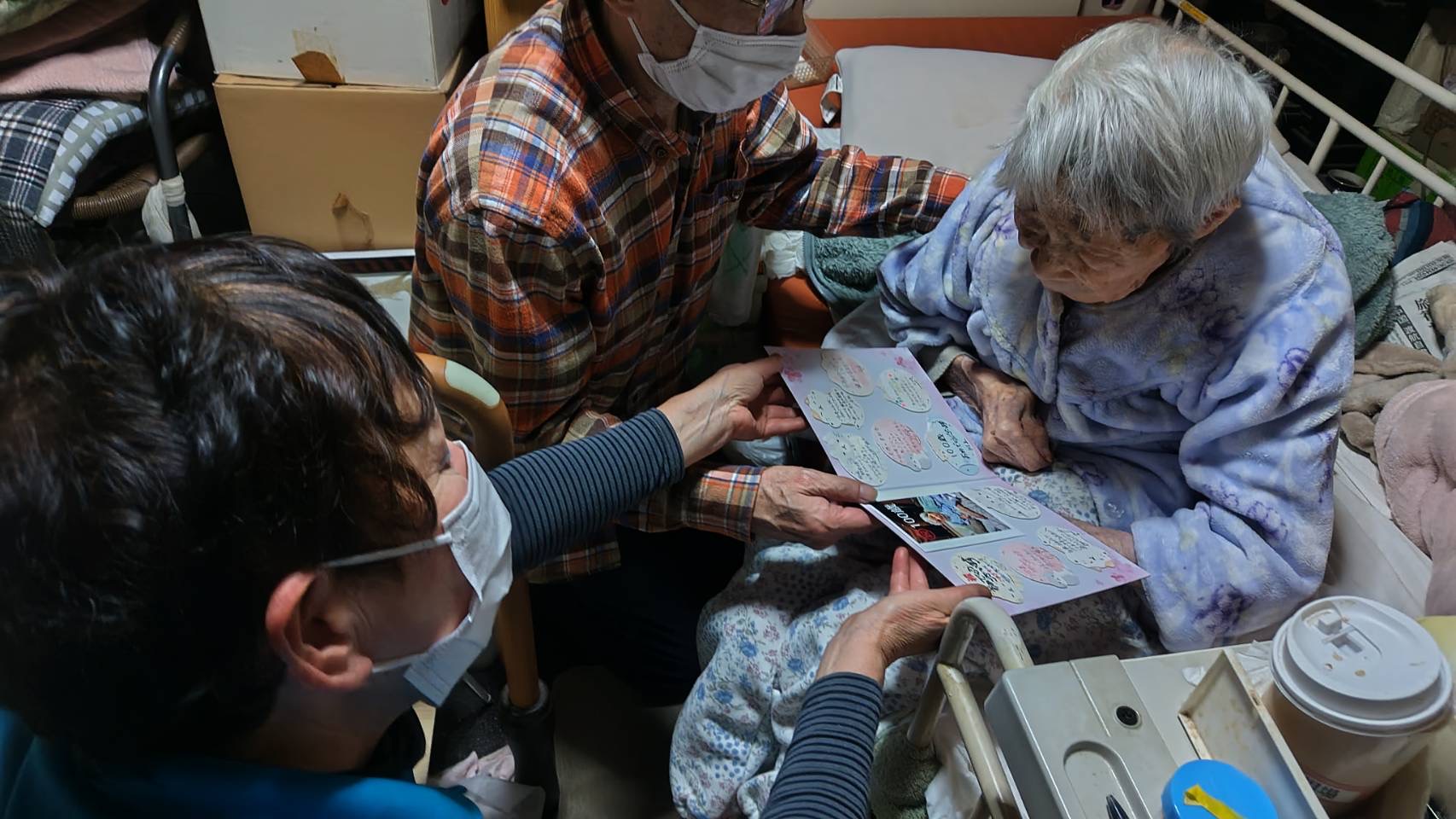 ヘルパーがプレゼントしたお祝いの色紙を息子様と利用者様で見ている