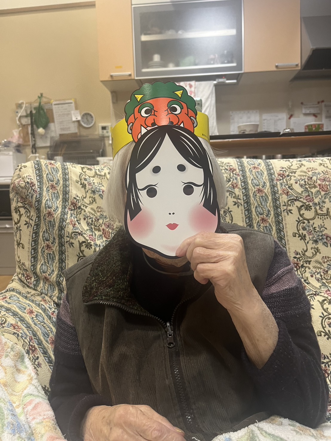 おかめの面をつけて写る利用者さん