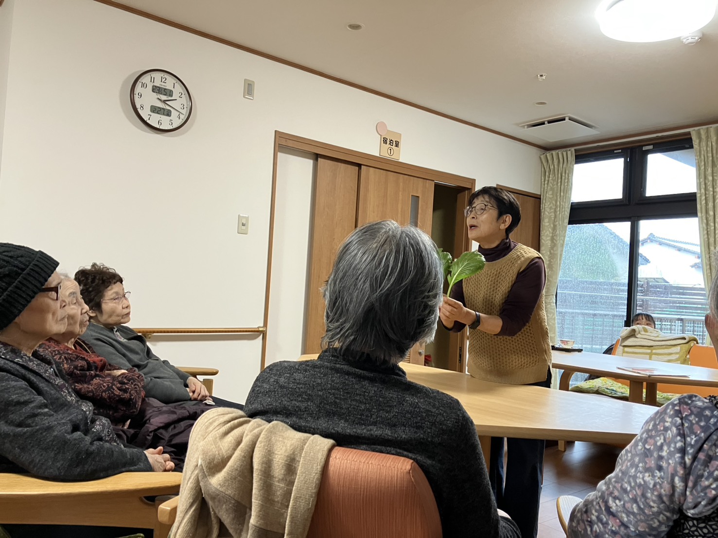 手に野菜を持ってお話するボランティアさん