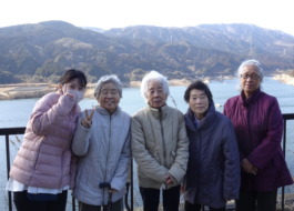 五ケ山ダムで山をバックに写る利用者たちとワーカー